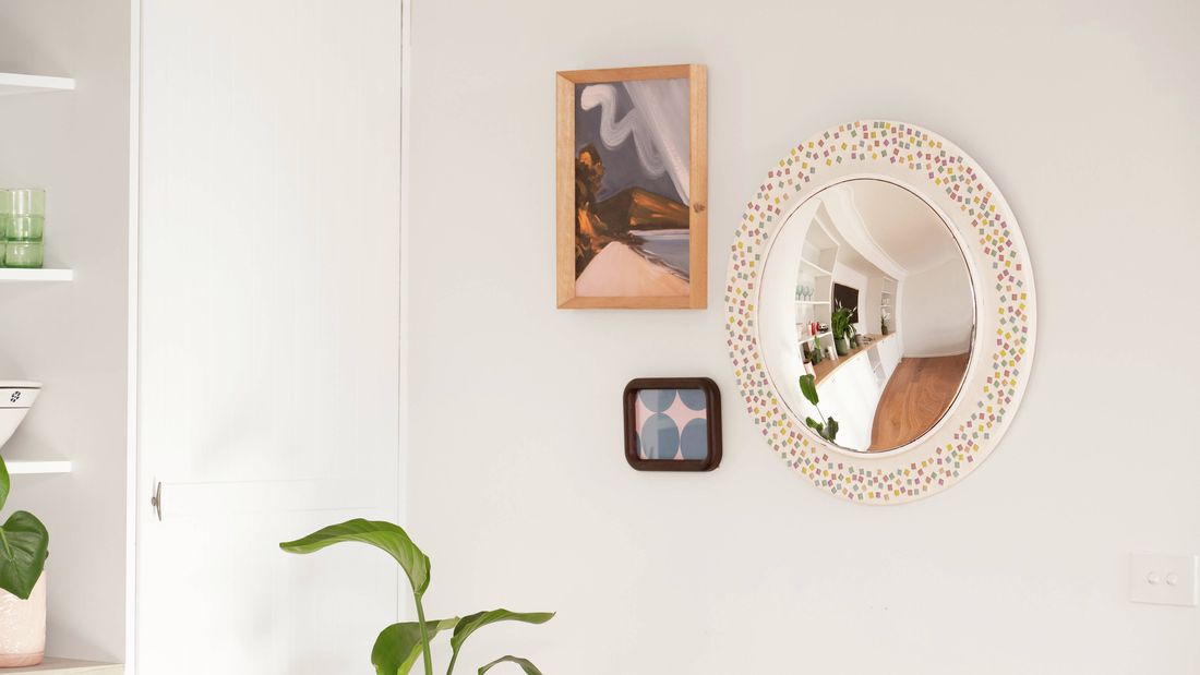 A finished arrangement of framed artwork and a decorative mirror shows how picture hangers can be used to securely display different types of wall décor while minimising wall damage