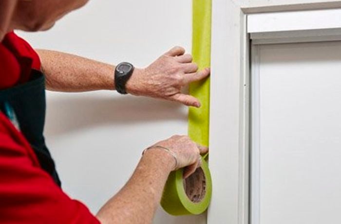 Person putting painters tape on the wall.