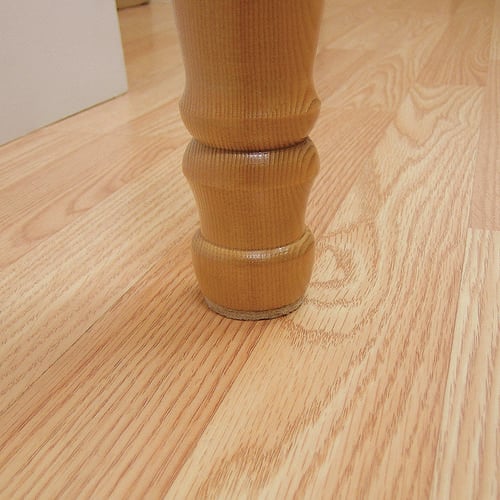 Base of table leg with floor surface protection adhesive