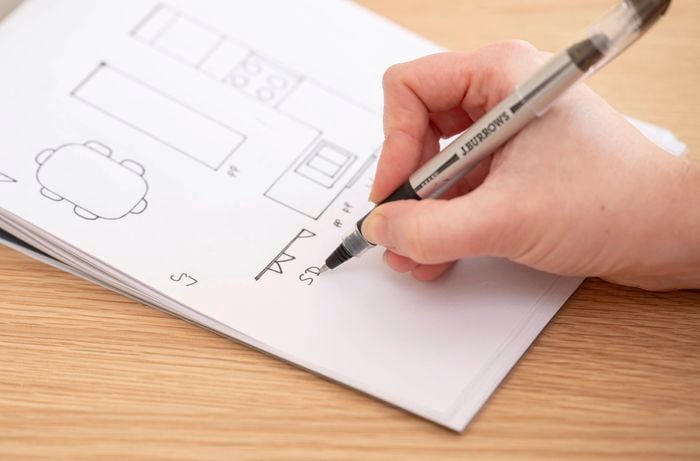 A person marks a kitchen sketch with symbols like “SD” , “PP”to clearly show important features like doors, windows, and power points. 