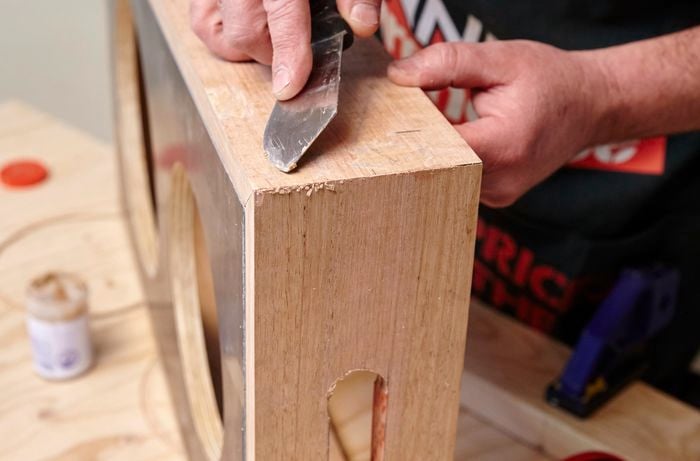 A person filling nail holes in timber using a putty knife