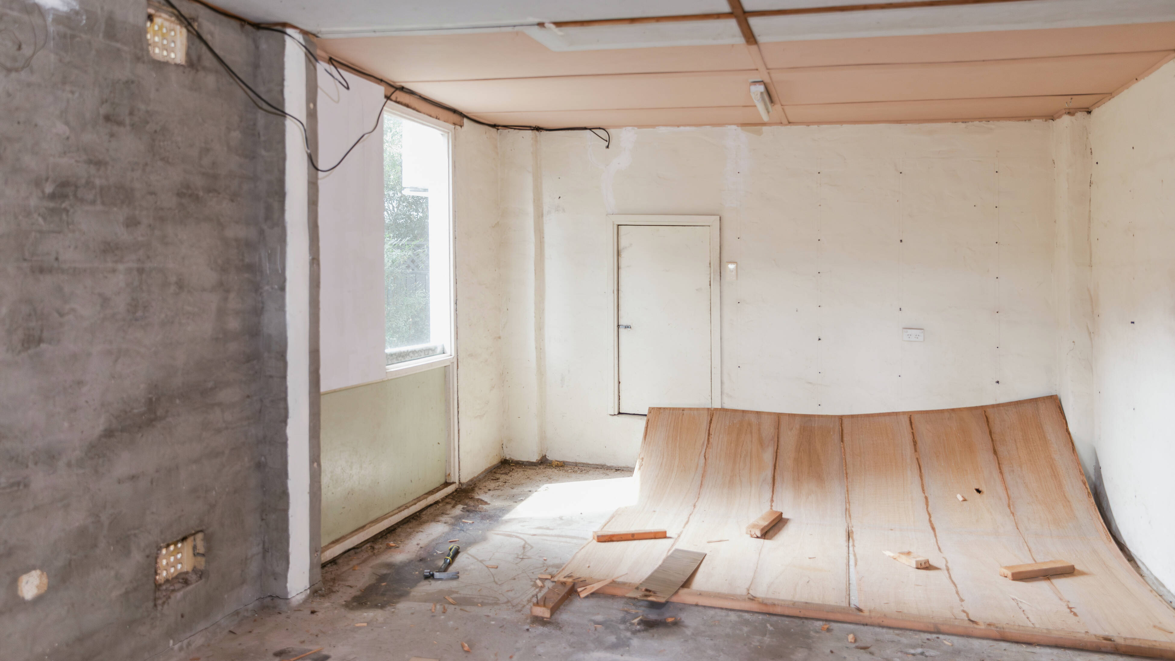 Damaged garage interior during demolition, showing exposed walls and removed flooring.