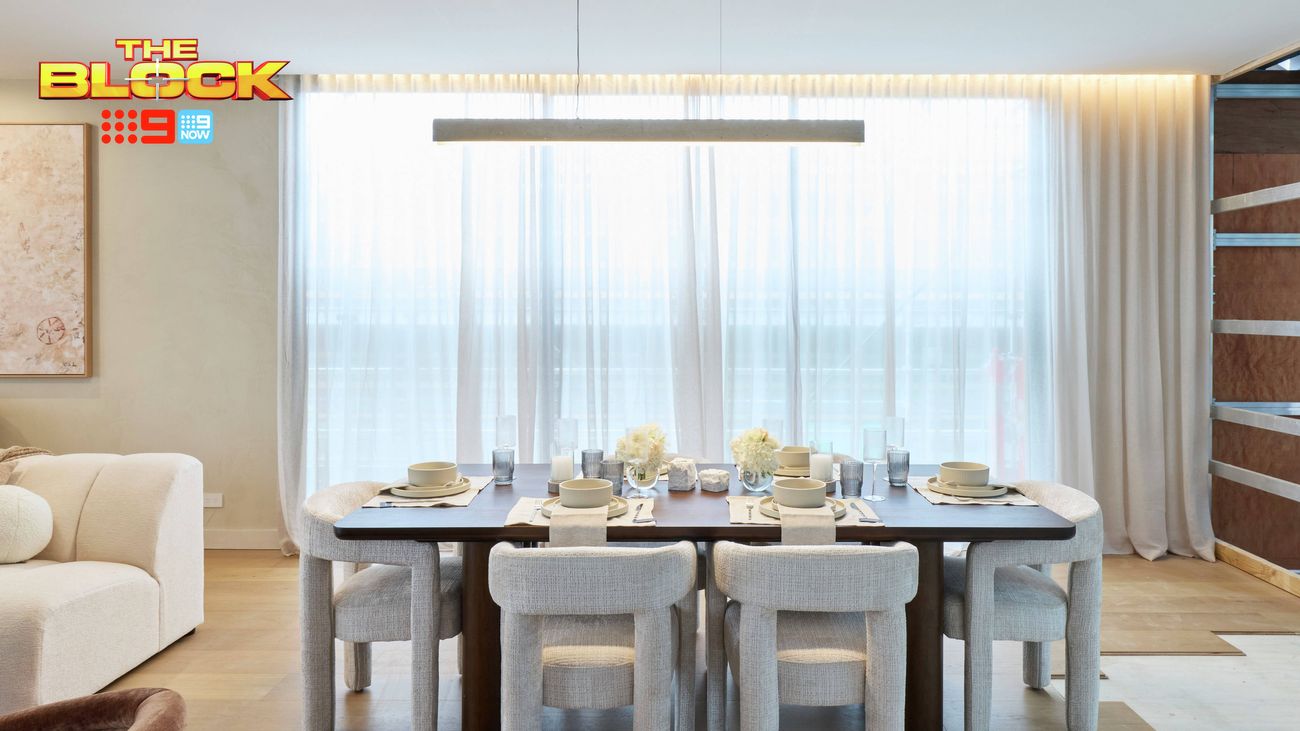 Contemporary dining area featuring a dark timber table, upholstered chairs, modern pendant light and floor-to-ceiling sheer curtains.