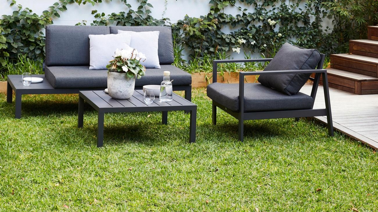Outdoor furniture on a healthy green lawn next to a garden wall and deck
