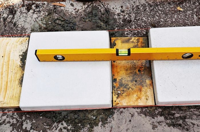 A spirit level laid across two pavers