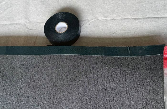 A black roll of double-sided tape sits next to a foam turf mat with a tip of a pool noodle hanging out