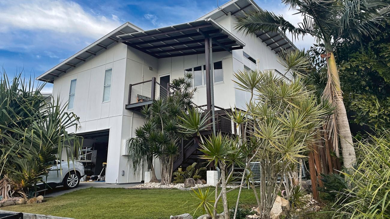Two-storey Queensland home with faded exterior cladding.