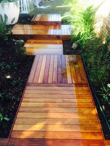 Tiered decking leading through a back garden to a small lawn