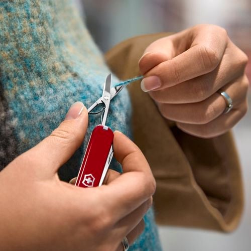 A person cutting a loose thread on a jumper.