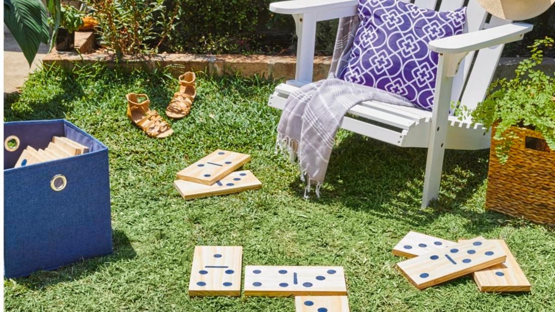 Large dominoes made of plywood on a lawn next to a wooden chair