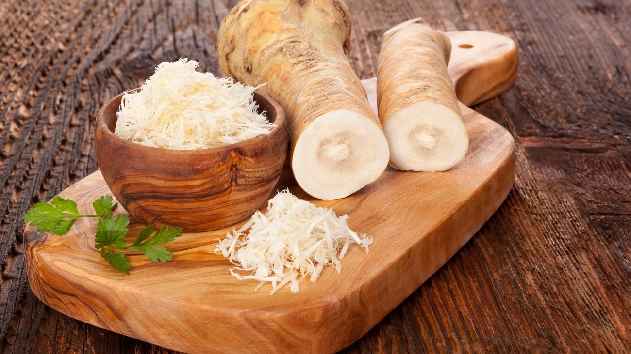Horseradish on a chopping board and some grated in a bowl