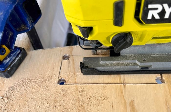Ryobi drill cutting a rectangular shape into piece of wood with clamp attached