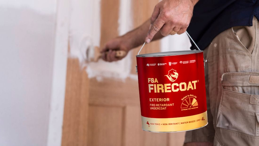 Person holding FSA FIRECOAT exterior undercoat paint, whilst painting a door.