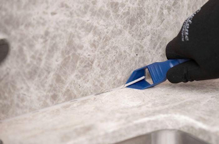 Remove silicone sealant from a benchtop joint with a scraper tool