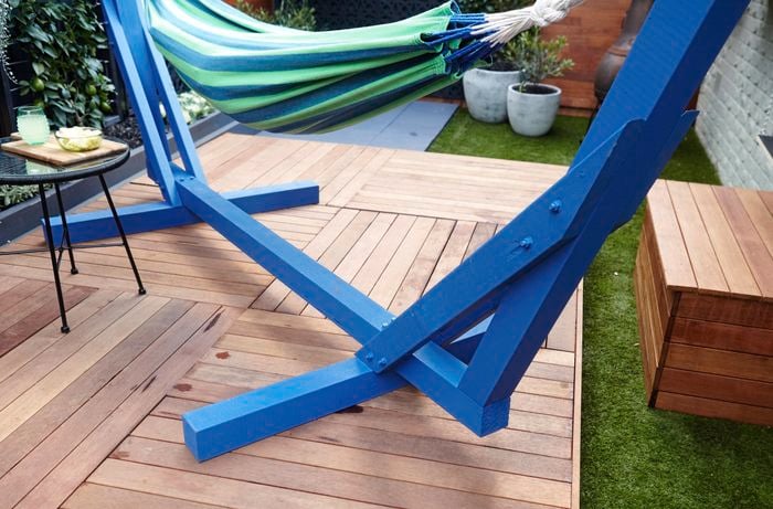 Outdoor decking area with blue hammock frame on it.