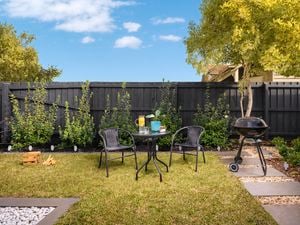 An outdoor table and chair setting on a grass lawn in a garden.