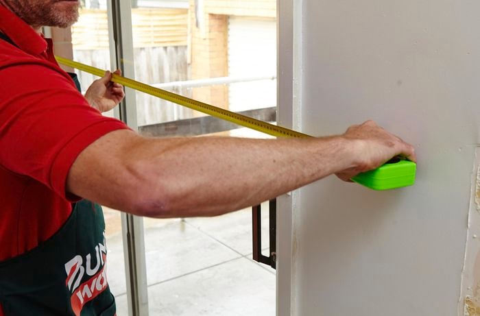 A person measuring across a double sliding glass door