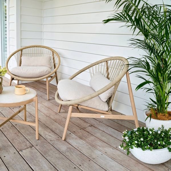 Cane outdoor setting and plants on a veranda outside.