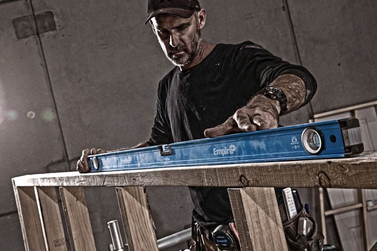 A gritty picture of a man using a spirit level on a railing