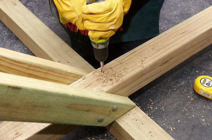 Person drilling holes into piece of timber.