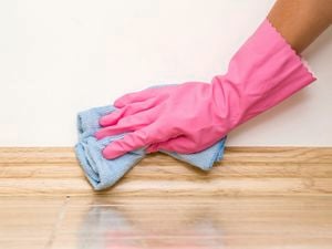Gloved hand using a micro-fibre cloth to wipe skirting boards.