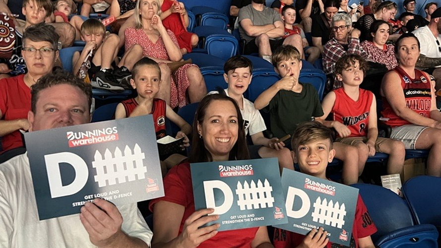 Family holding D signs and watching basketball game