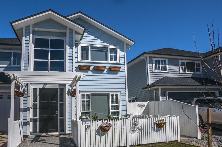 Exterior of a pale blue two-storey weatherboard house with white trim and dark grey front door