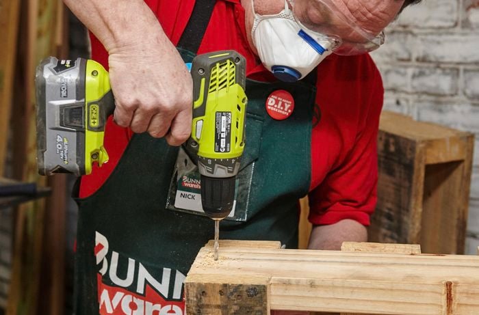 A hole being drilled into the frame of a pallet wine bar frame for a screw