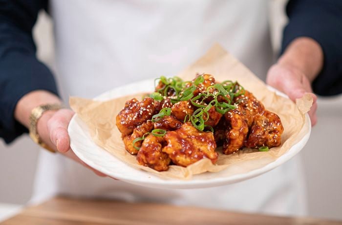 A person is holding a plate of crispy Korean fried cauliflower