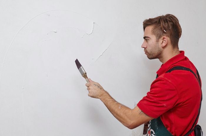 Water being flicked onto a wall with a paintbrush to smooth over before it completely dries