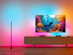 Living room with a TV showing an underwater reef scene, surrounded by colourful ambient smart lighting on walls and ceiling.