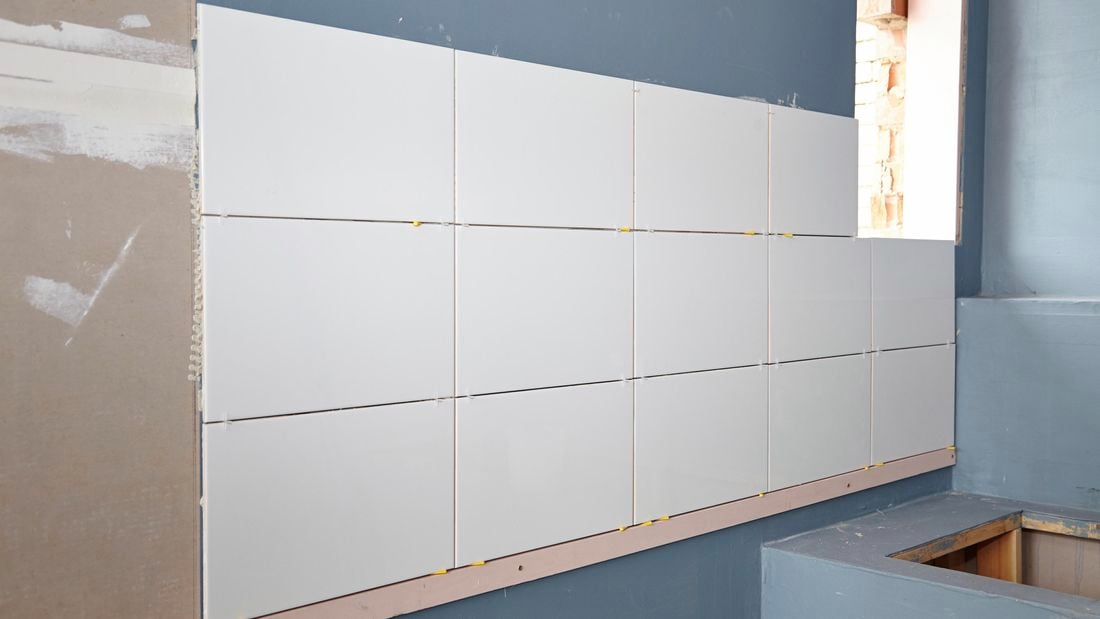 Freshly laid white tiles on bathroom wall.