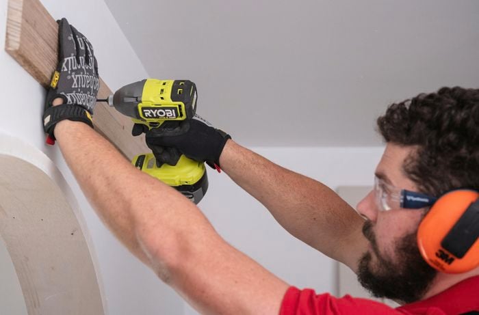 Team member attaching mounting board to a wall with a drill.