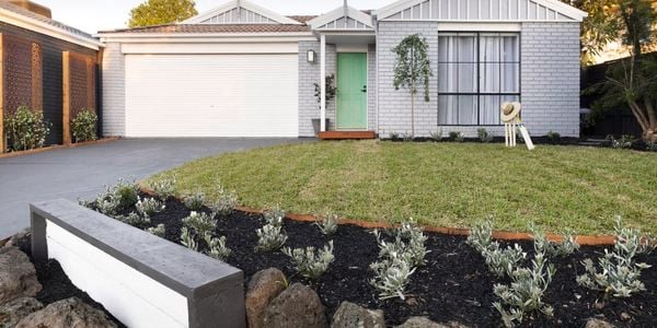 Brick house painted grey with a lawn, garden and concrete driveway.