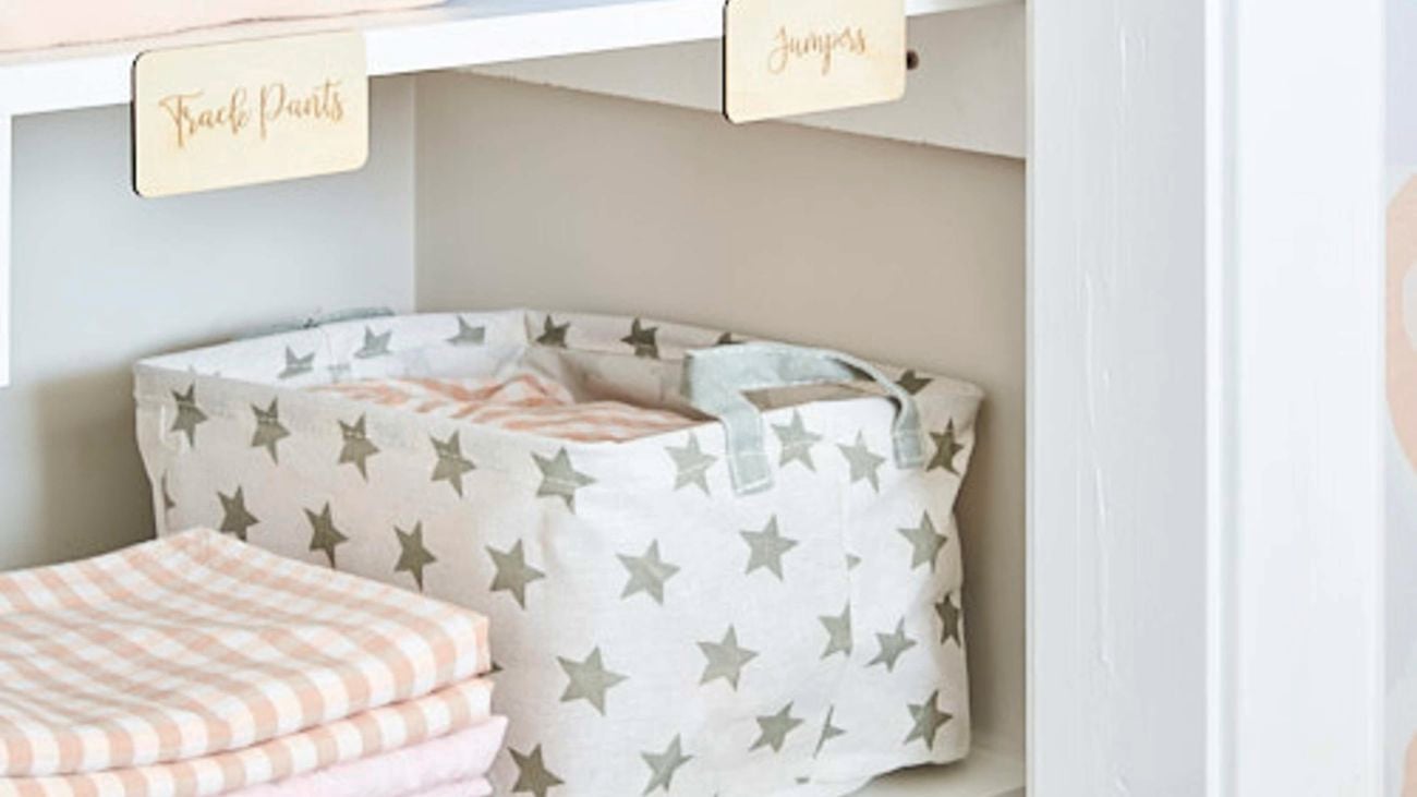Shelves in a wardrobe holding neatly folded clothes and some storage boxes.