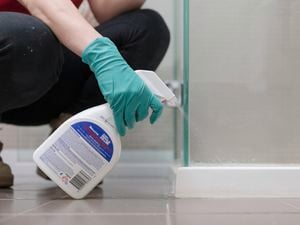 A person with green gloves is spraying Selleys mould killer onto the affected surface.