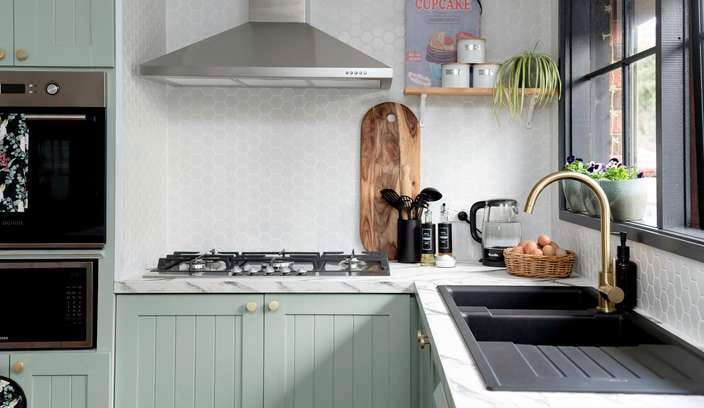Kitchen with green cupboards and marble benchtop.