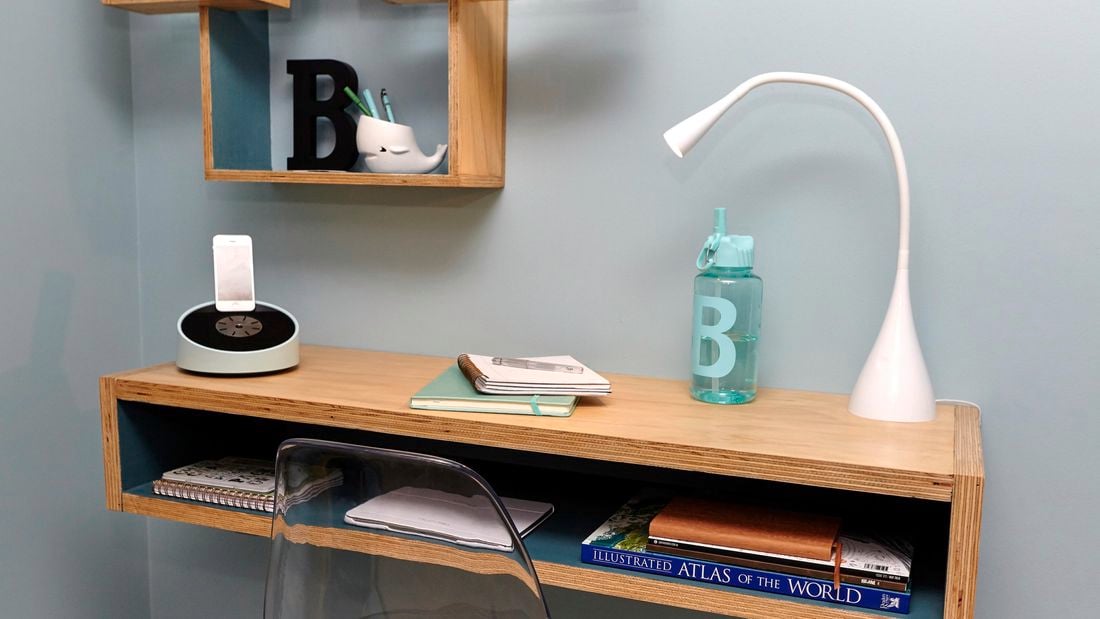 A lamp and book on a floating timber desk attached to a wall