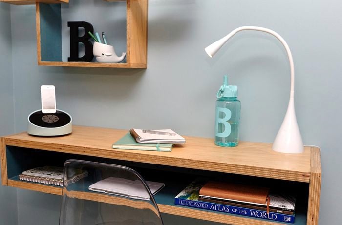 A lamp and book on a floating timber desk attached to a wall