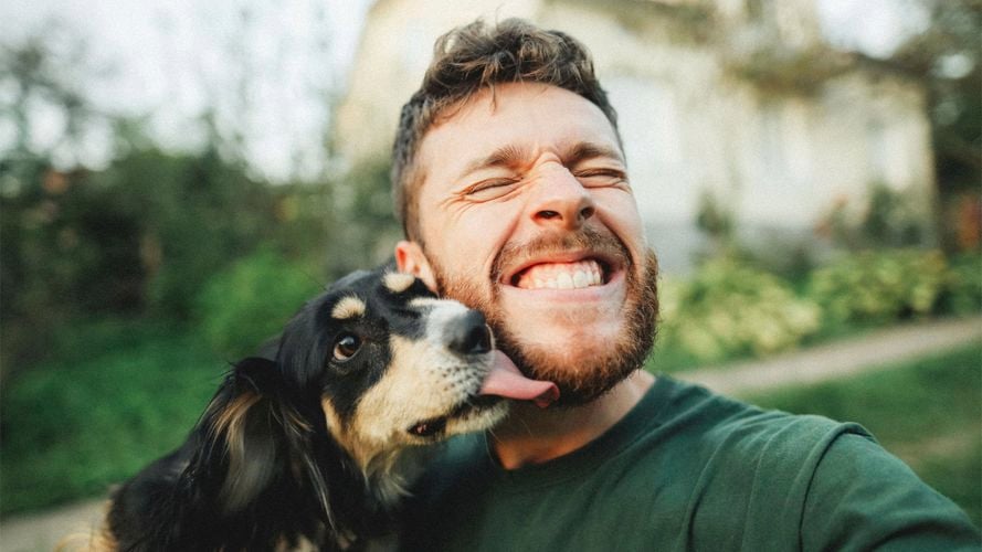 A man with a dog licking his face.