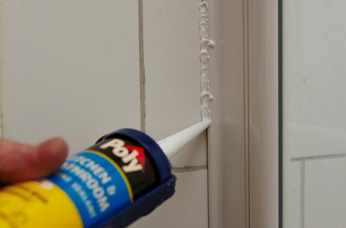 Caulking gun inserting silicone sealant into a crack.