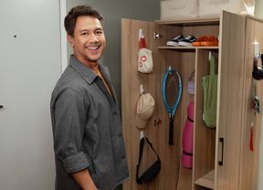 Person standing in front of a cupboard with Command hooks holding up accessories.