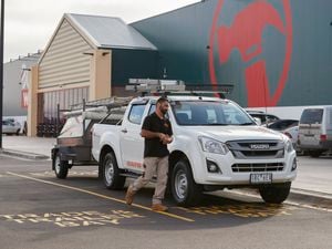 Bunnings customer standing in front of his white work ute in a bunnings carpark