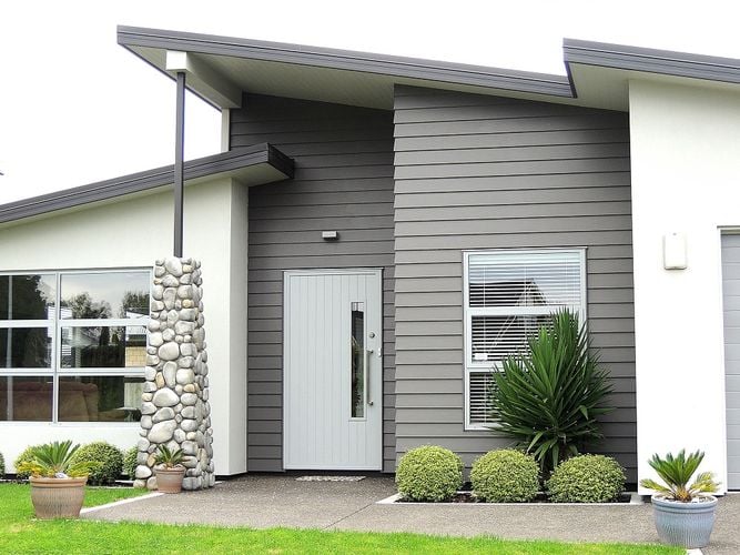 Exterior of a house painted mid-grey and white with a white front door