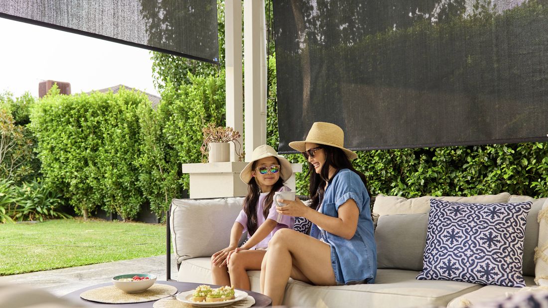 Outdoor patio with Coolaroo outdoor blinds lowered to provide shade over a seating area.