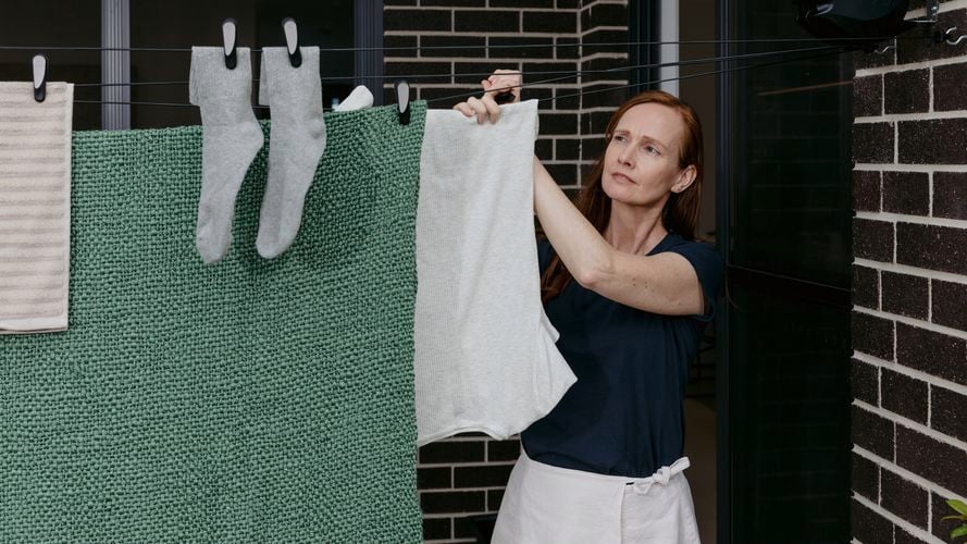 Woman hanging washing on a Hills Double Retracting Clothesline.