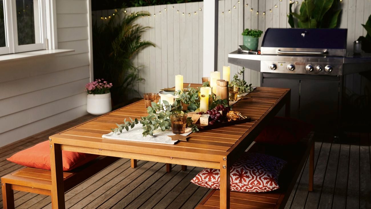 A New Year's Eve outdoor table set up at night time decorated with candles and foliage.