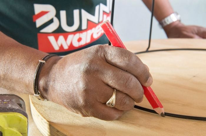 Person marking hole locations on base of tabletop