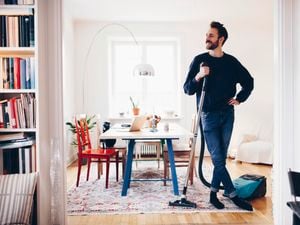 A man holding the Britex carpet cleaner in his hand in a living room.