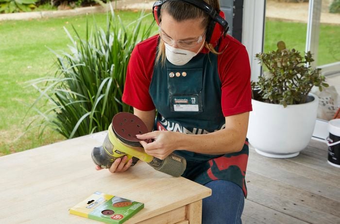 Person applying abrasive disc to orbital sander.